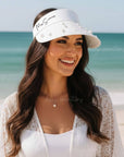 Woman wearing a white visor with 'Mrs. Smith' text on a beach at her bachelorette party.
