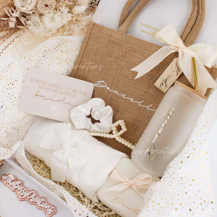 Gift Box for Bride to be with personalized tote bag with bow and wooden tag, custom glass tumbler with gold straw, luxury velvet jewelry box, satin hair tie and pearl hair claw, white satin robe. handmade by bossy creations